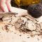 Découpe au couteau de truffe sur une planche en bois, lamelles et deux belles truffes