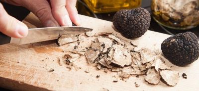Découpe au couteau de truffe sur une planche en bois, lamelles et deux belles truffes